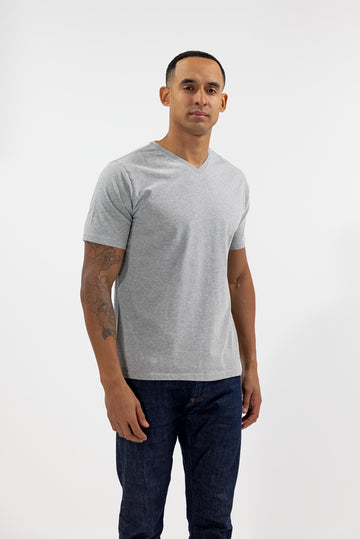 angled front view of model wearing Easy Mondays light grey heather colored V neck tee shirt