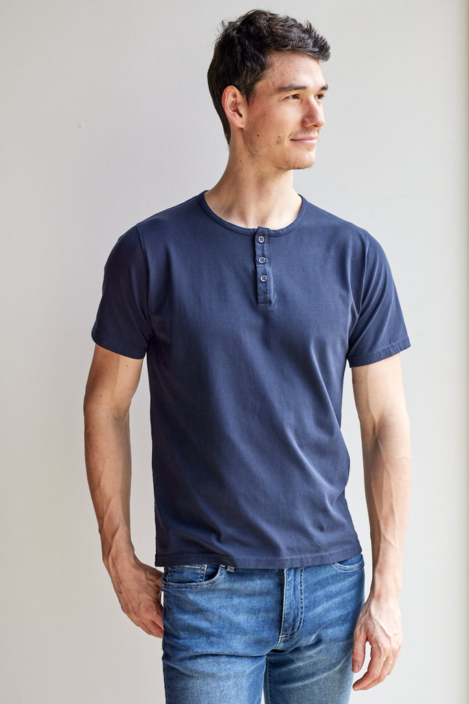 front view of model wearing Easy Mondays dark blue navy colored short sleeved Henley shirt with color-matched buttons