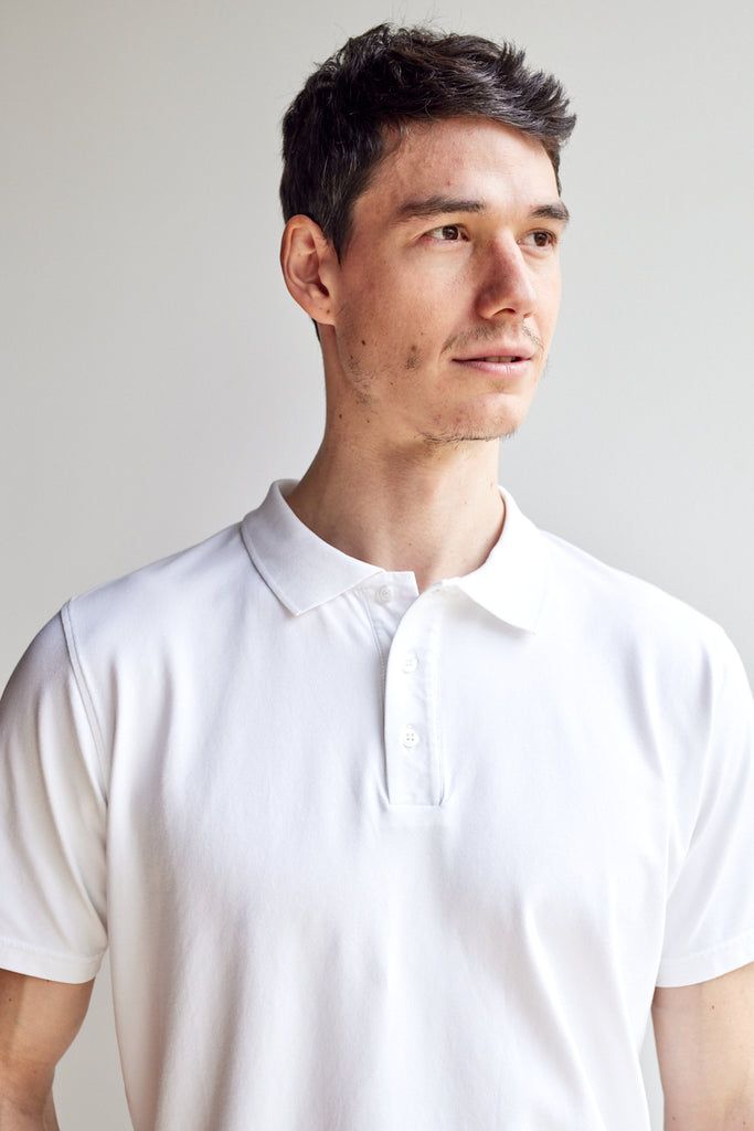 close up front view of model wearing Easy Mondays off white colored polo shirt with color-matched buttons