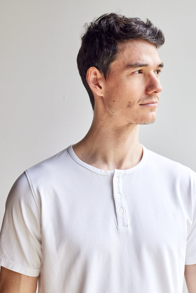 close up of model wearing Easy Mondays off white colored short sleeved Henley shirt with color-matched buttons