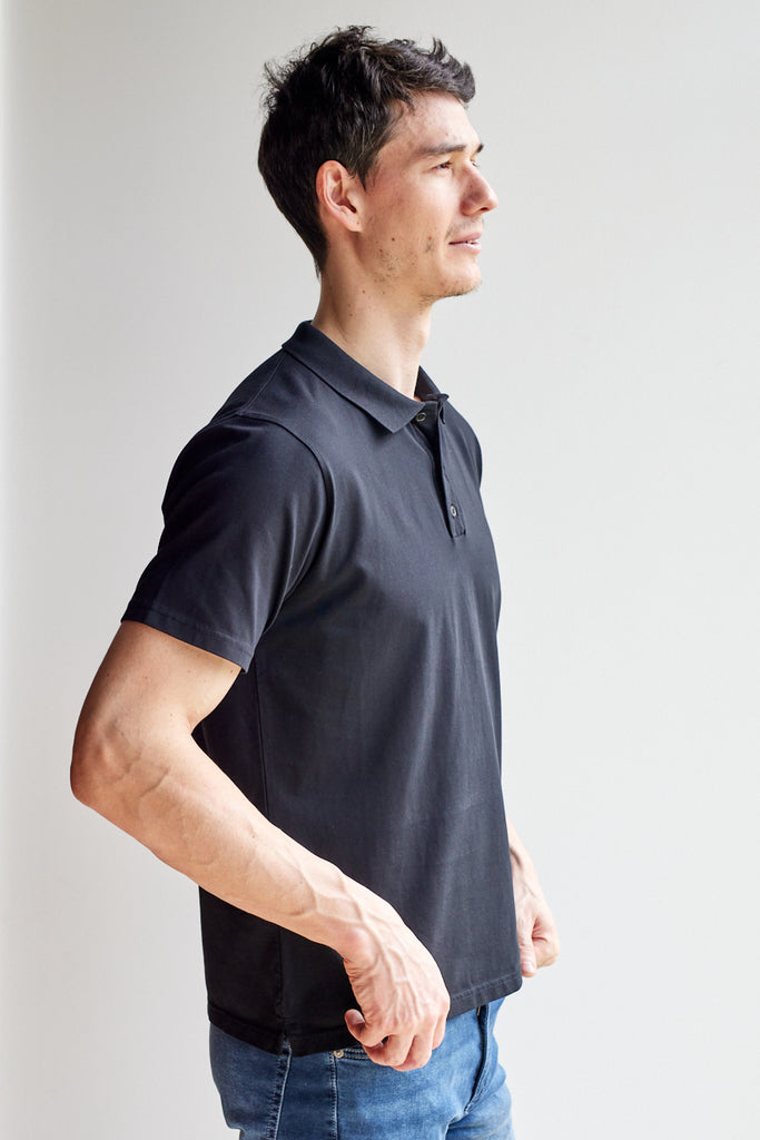 side view of model wearing Easy Mondays black short sleeved polo shirt with color-matched buttons