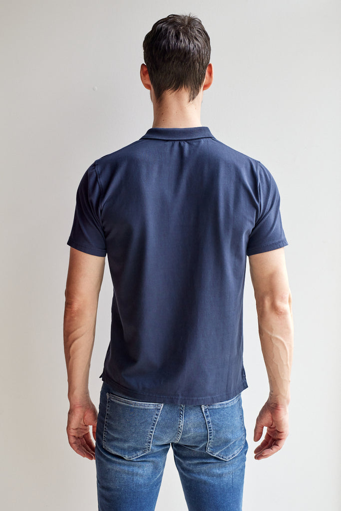 back view of model wearing Easy Mondays dark blue navy colored polo shirt with color-matched buttons