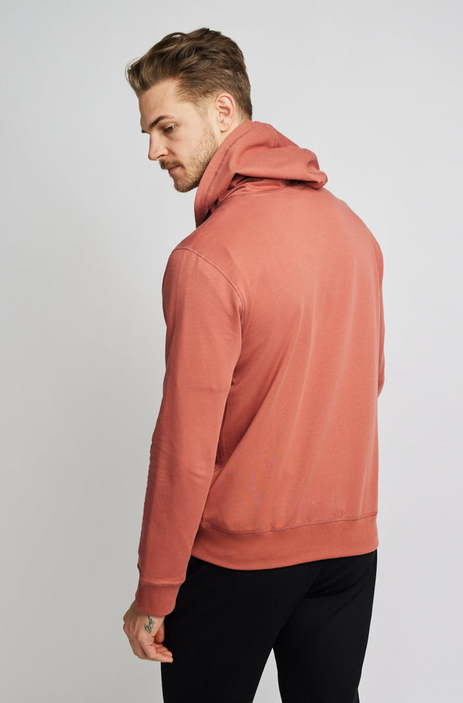 back of model wearing Easy Mondays brand hoodie jacket in light pink salmon color