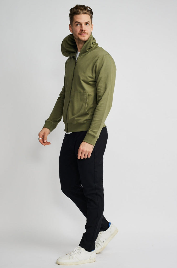 angled side view of model wearing Easy Mondays brand hoodie jacket in light forest green sage color fully zipped