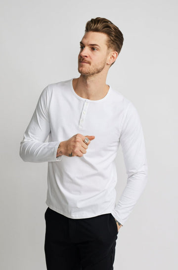 front of model wearing Easy Mondays brand long-sleeved white henley shirt with color matched buttons