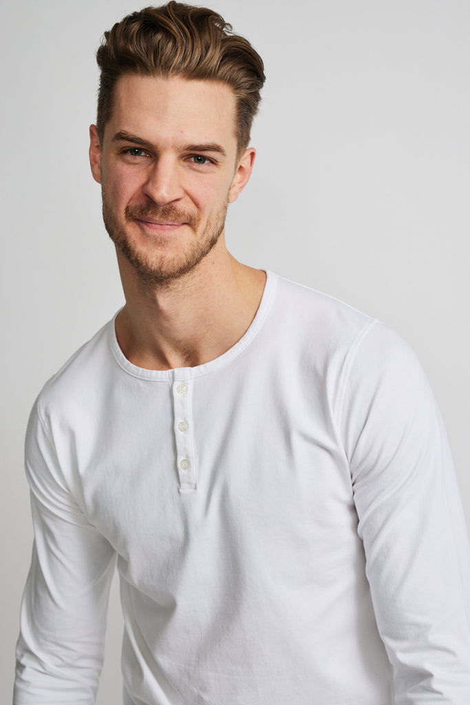 close up of front of model wearing Easy Mondays brand long-sleeved white henley shirt with color matched buttons