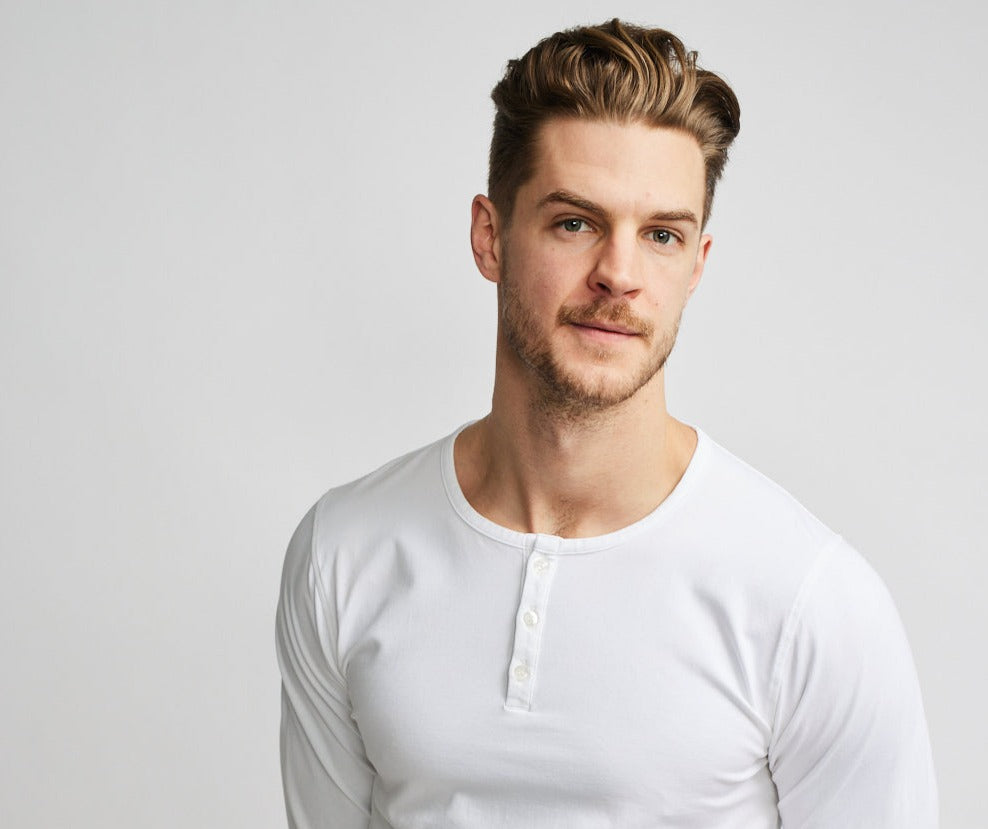close up from chest upward of model wearing Easy Mondays brand long-sleeved white henley shirt with color matched buttons