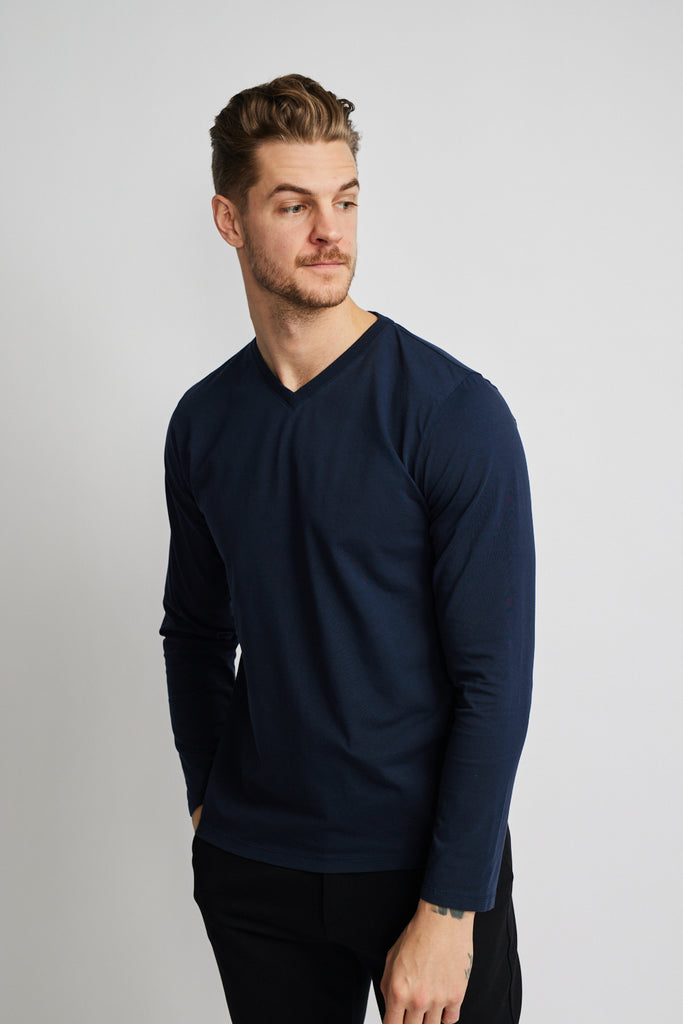 angled side view of model wearing Easy Mondays brand v neck long sleeved shirt in dark blue navy color