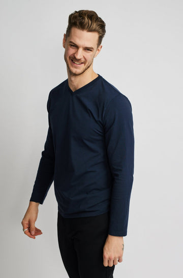 angled front view of model wearing Easy Mondays brand v neck long sleeved shirt in dark blue navy color