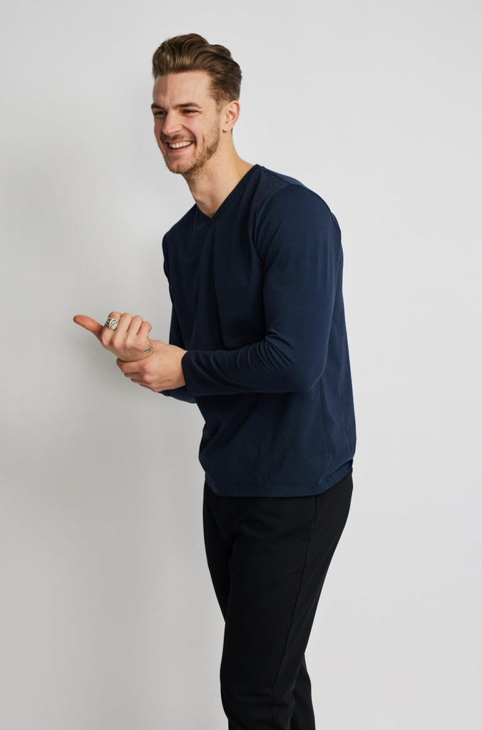 angled side view of model wearing Easy Mondays brand v neck long sleeved shirt in dark blue navy color pointing offscreen