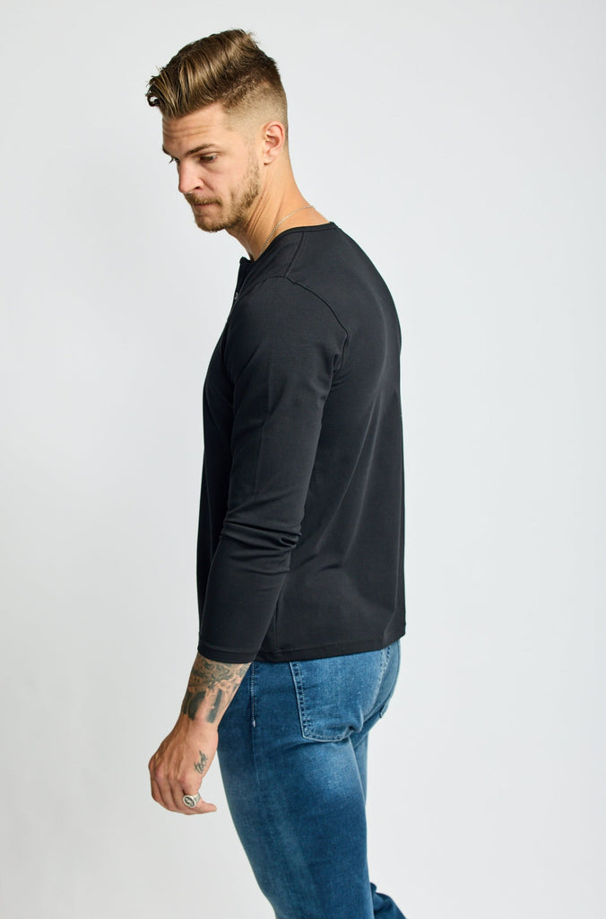 side view of model wearing Easy Mondays brand black Henley shirt with color matched buttons