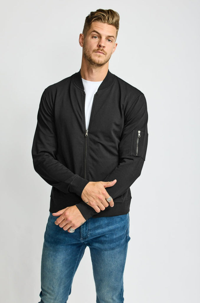 front of model wearing Easy Mondays brand full-zip black fleece bomber jacket halfway zipped up 
