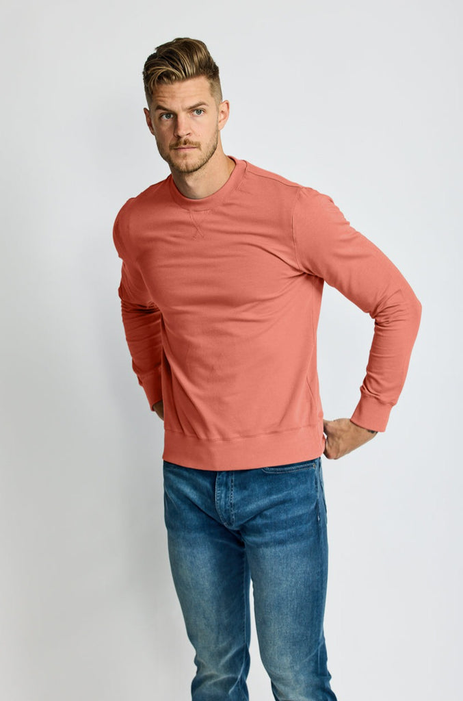 front of model wearing Easy Mondays brand crew neck sweatshirt in light pink salmon color