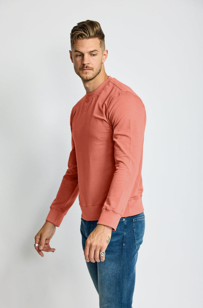 side view of model wearing Easy Mondays brand crew neck sweatshirt in light pink salmon color