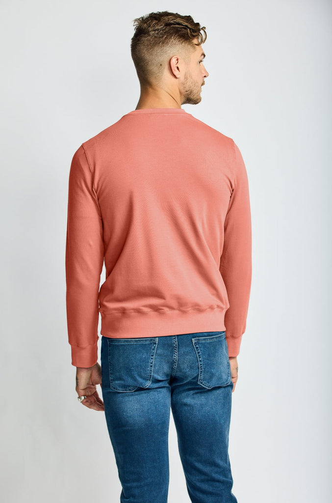 back of model wearing Easy Mondays brand crew neck sweatshirt in light pink salmon color