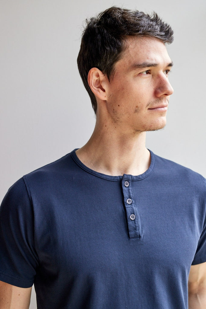 close up of model wearing Easy Mondays dark blue navy colored short sleeved Henley shirt with color-matched buttons