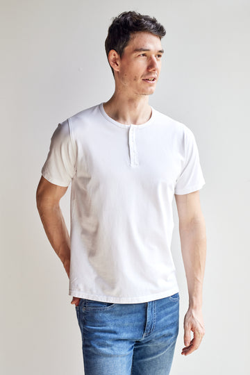 front view of model wearing Easy Mondays off white colored short sleeved Henley shirt with color-matched buttons