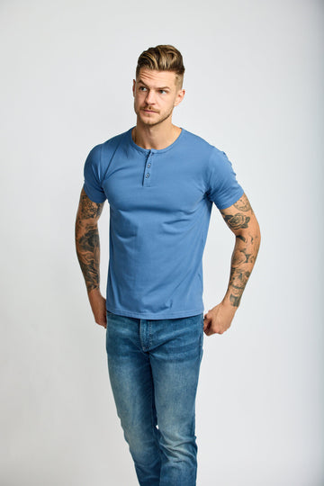 front of model wearing Easy Mondays short sleeved Henley shirt in light ocean blue with color matched buttons