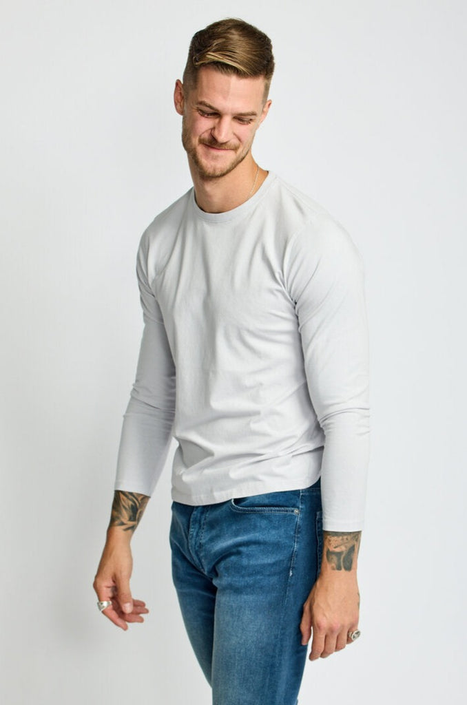side view of model wearing Easy Monday long sleeve crew neck sweater in off-white cloud color with straight arms
