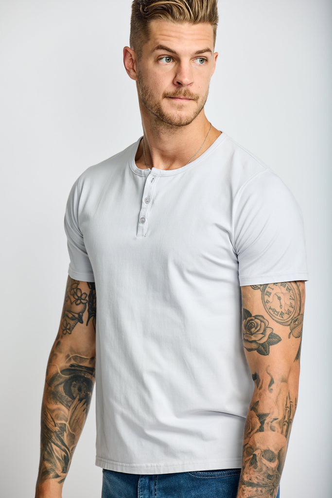 close up of model wearing Easy Mondays short sleeved Henley shirt in off white cloud color with color matched buttons